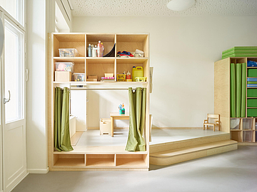 Großer Kindergartenraum mit Einbauten aus Holz und einem Spielpodest
